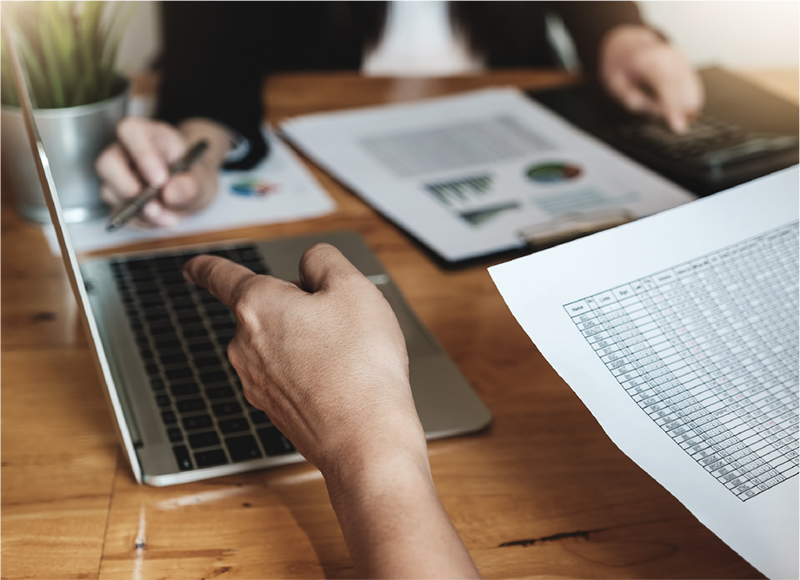 Two business men discussing graphs, spreadsheets and info on a laptop coomputer between them